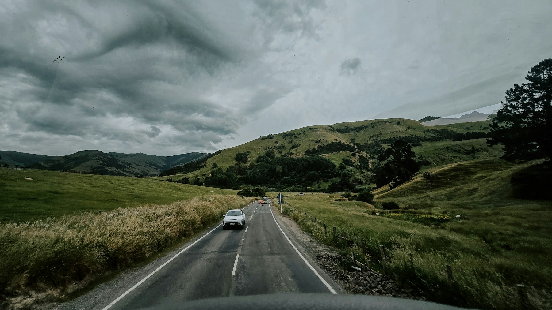 Cars travelling through green hills on a New Zealand road